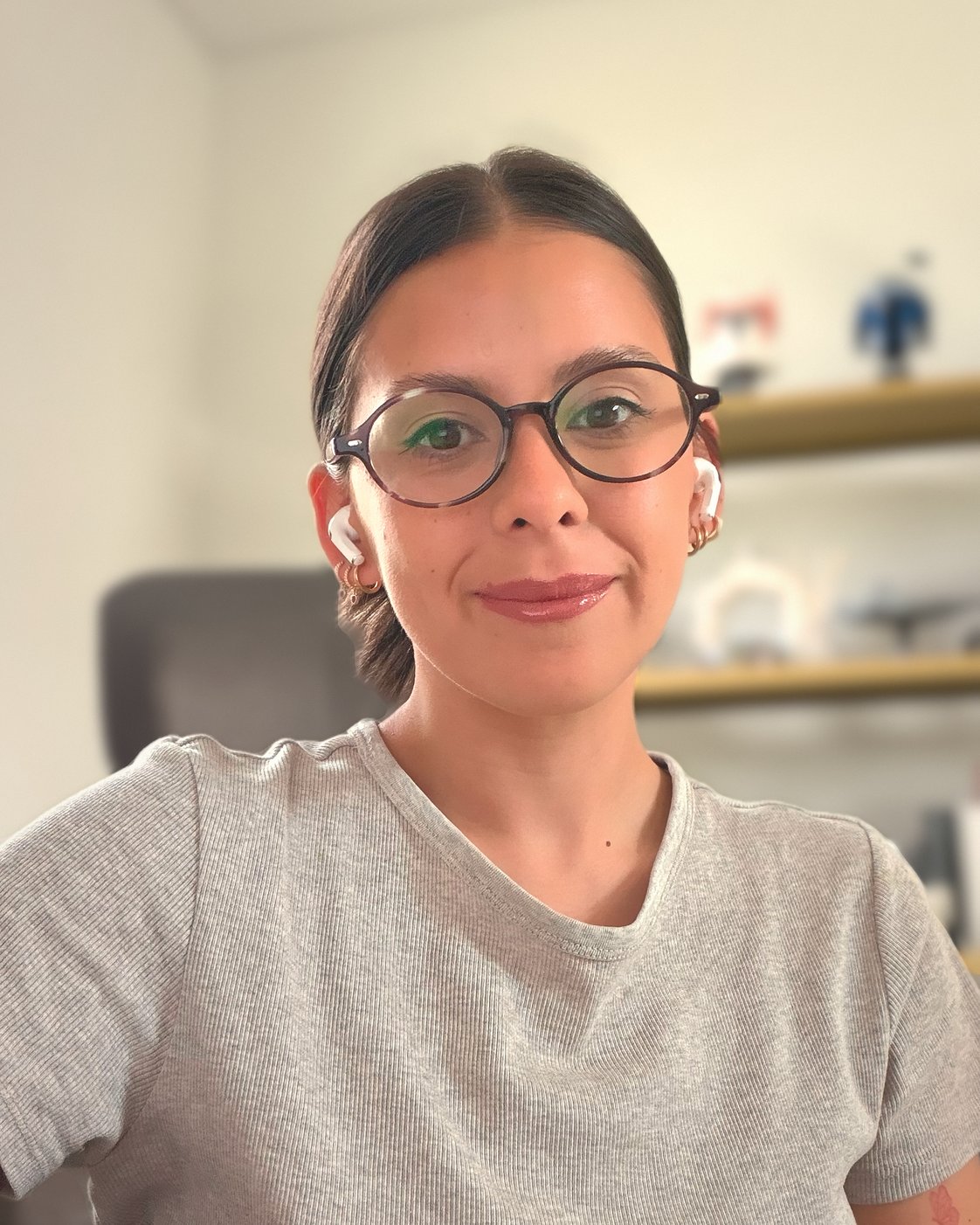 Portrait of Belu Guardia smiling, wearing round glasses